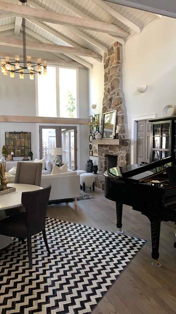 Remodeled living room with stone fireplace and wood beam ceilings