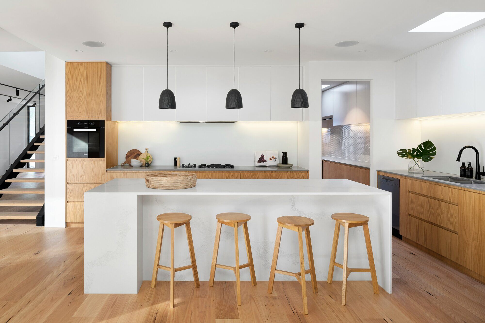 Open-concept kitchen with wood flooring, a large island, and modern pendant lights by Wolfe Construction, Jackson, TN