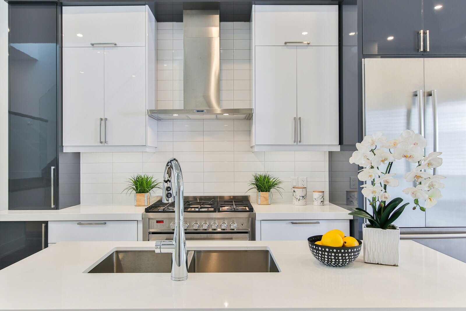 Sleek modern kitchen with white and grey cabinetry, polished countertops, and stainless steel appliances by Wolfe Construction, Jackson, TN