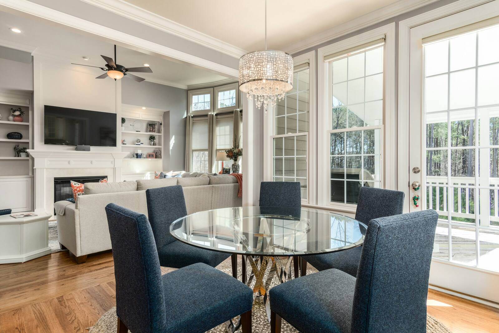 Home Additions - Elegant dining and living area with large windows, a glass table, and modern lighting by Wolfe Construction in Jackson, TN