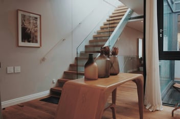 Custom-built entryway with glass railings, wooden stairs, and decorative vases - The Home Remodeling Process & Timeline - Wolfe Construction Co - West Tennessee - Home Builder & Remodeler