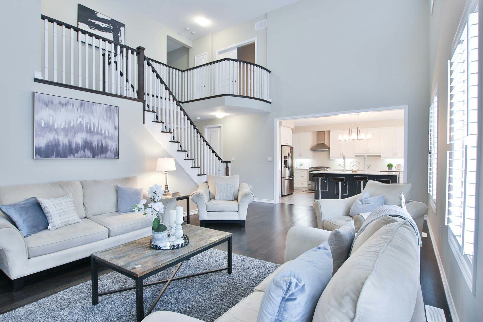 Open-concept living room with vaulted ceilings, white sofas, and dark wood accents by Wolfe Construction, Jackson, TN