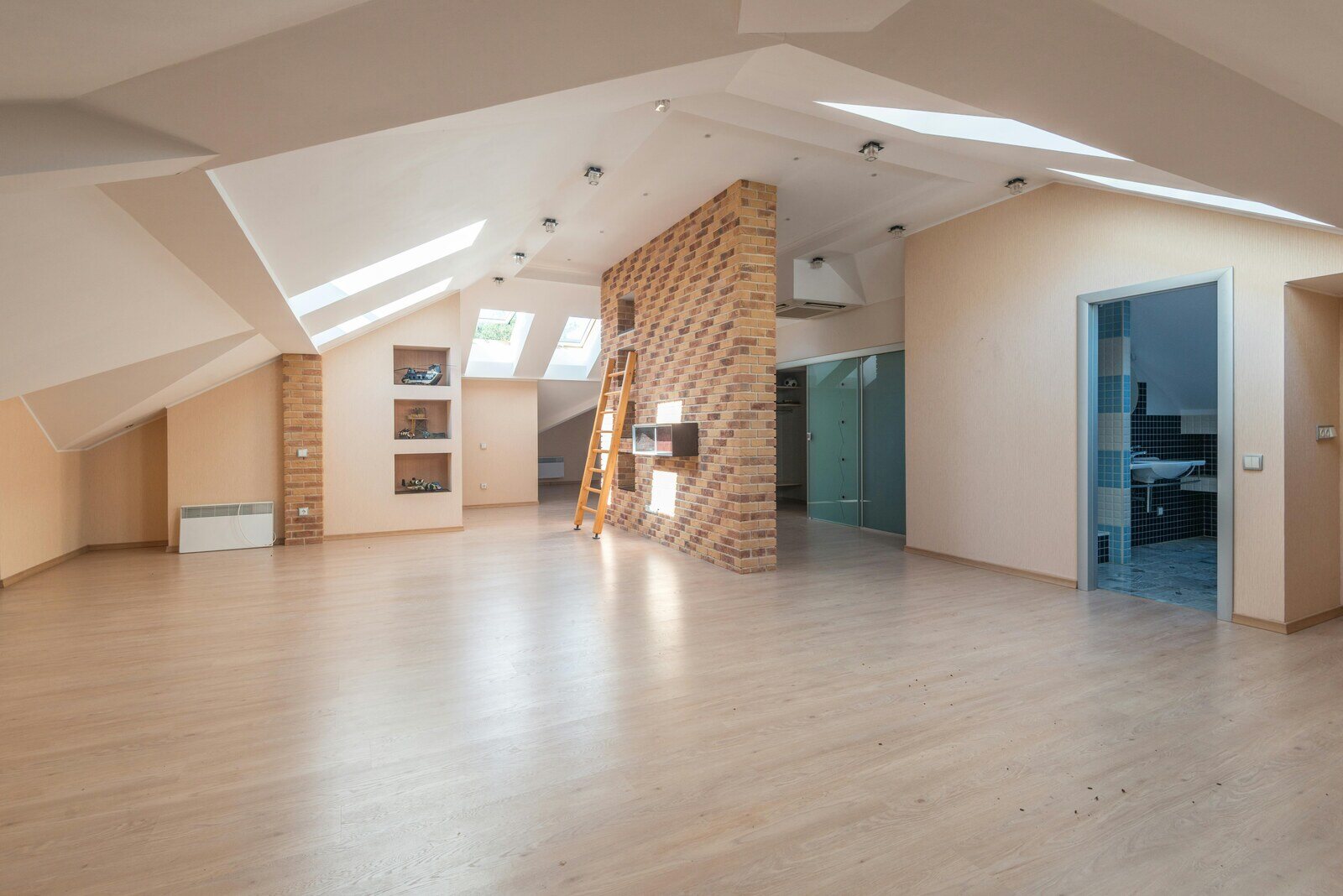 Spacious attic renovation with a brick accent wall, skylights, and open layout by Wolfe Construction in Jackson, TN