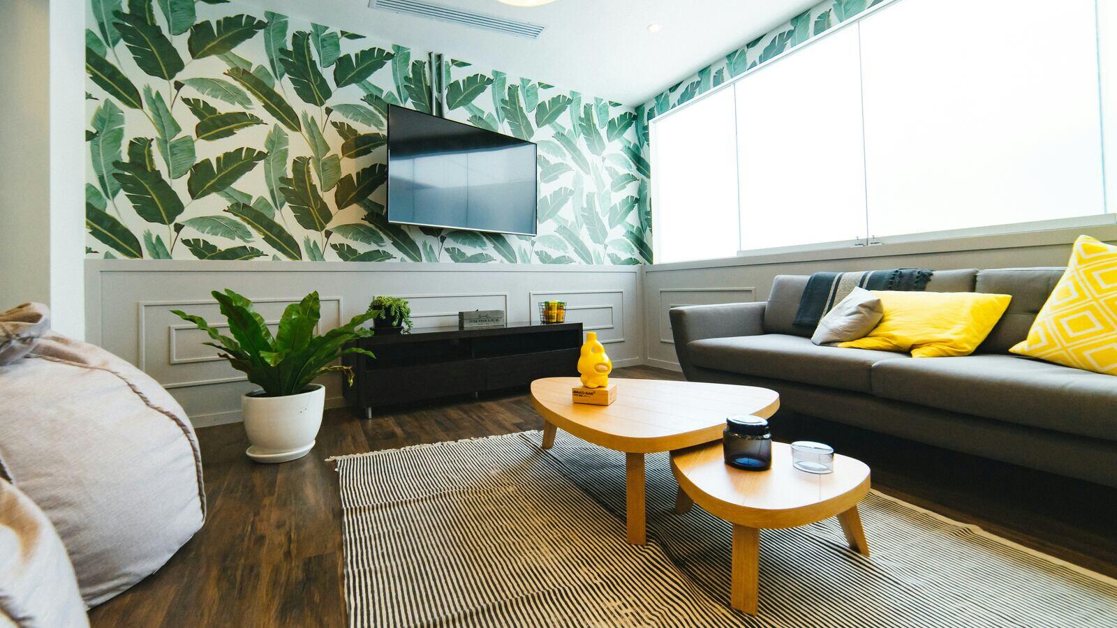 Stylish living room with tropical leaf wallpaper, a gray sofa, and modern decor - The Home Remodeling Process & Timeline - Wolfe Construction Co - West Tennessee - Home Builder & Remodeler