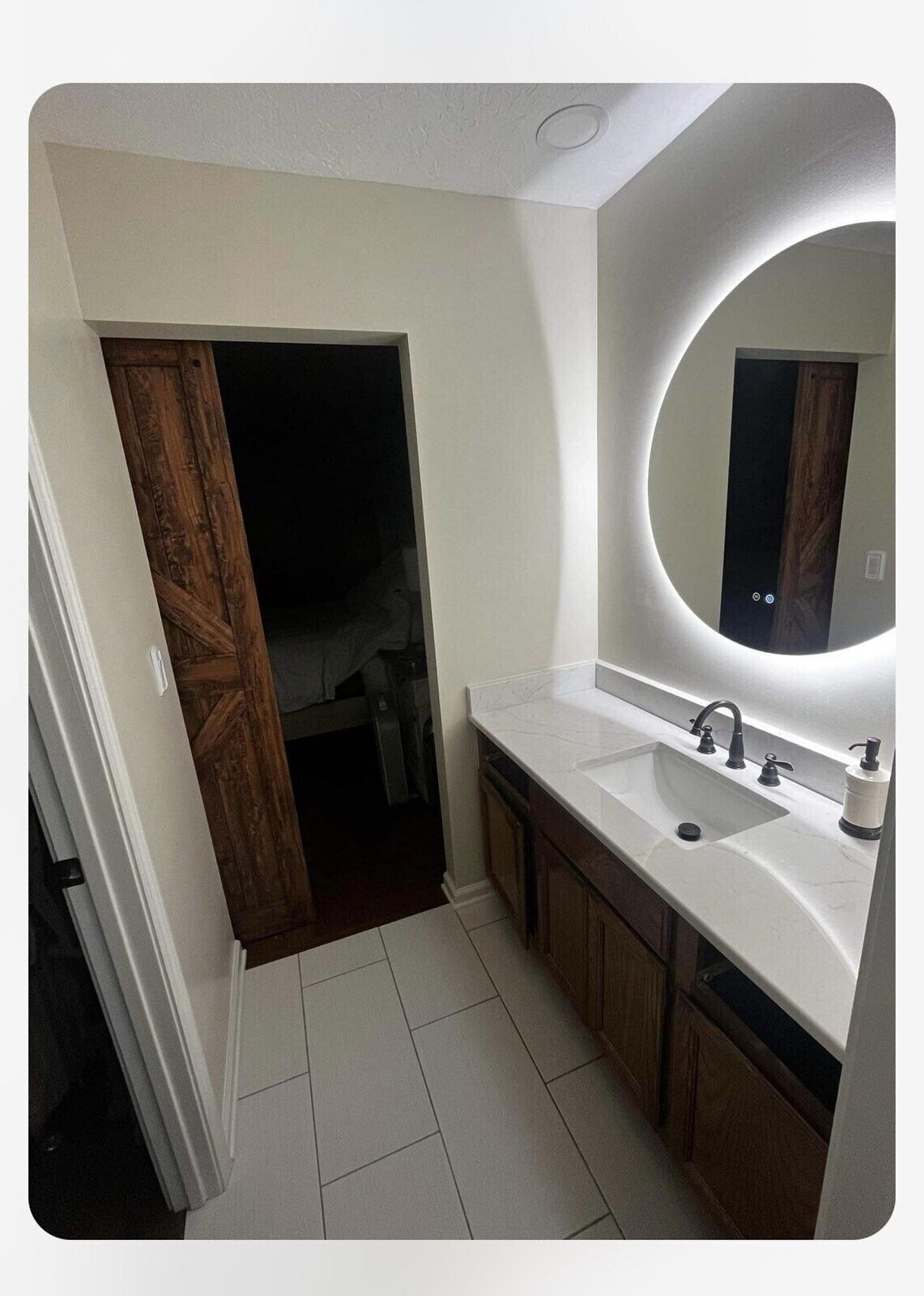 Modern bathroom vanity with a circular LED mirror and wood accents by Wolfe Construction in Jackson, TN