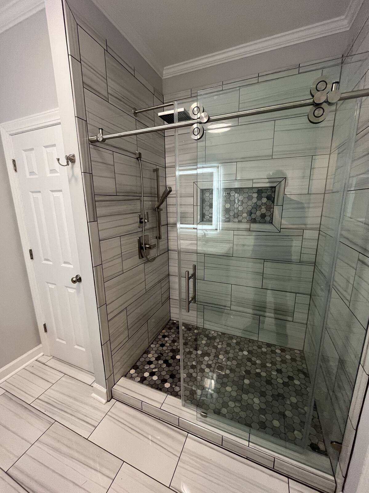 Polished glass shower with marble-look wall tiles and chrome hardware by Wolfe Construction in Jackson, TN