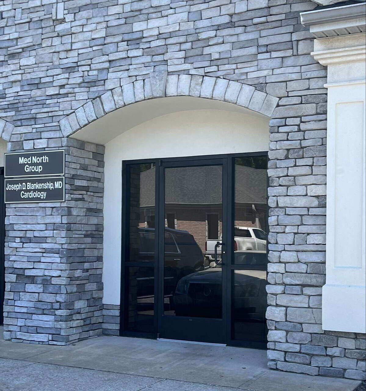 insurance restoration services - Entrance to a remodeled commercial office with a stone facade and new black-framed glass doors by Wolfe Construction in Jackson, TN