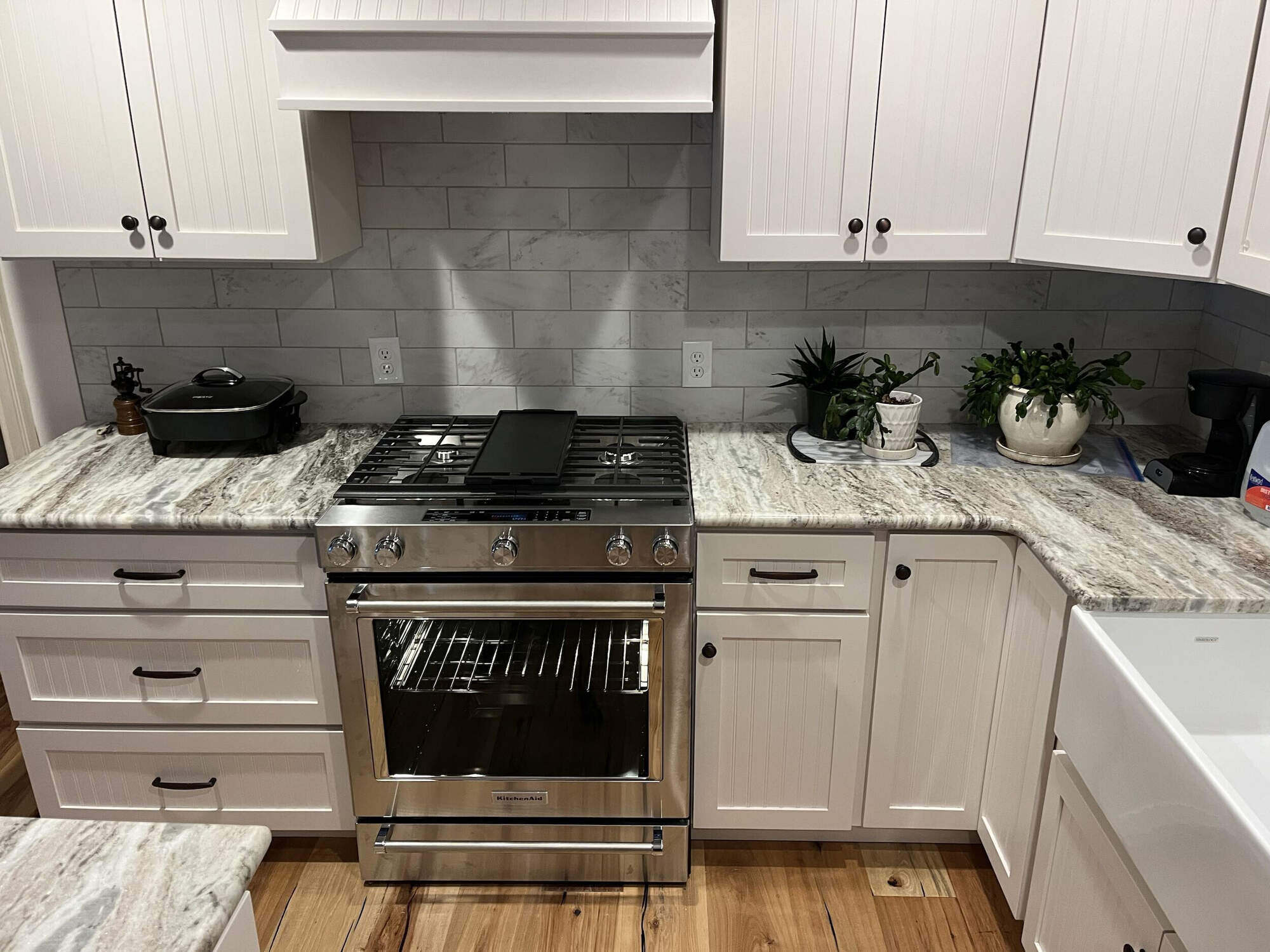 Updated kitchen featuring sleek white cabinetry, granite counters, and a modern stove, part of a remodeling project by Wolfe Construction in Jackson, TN